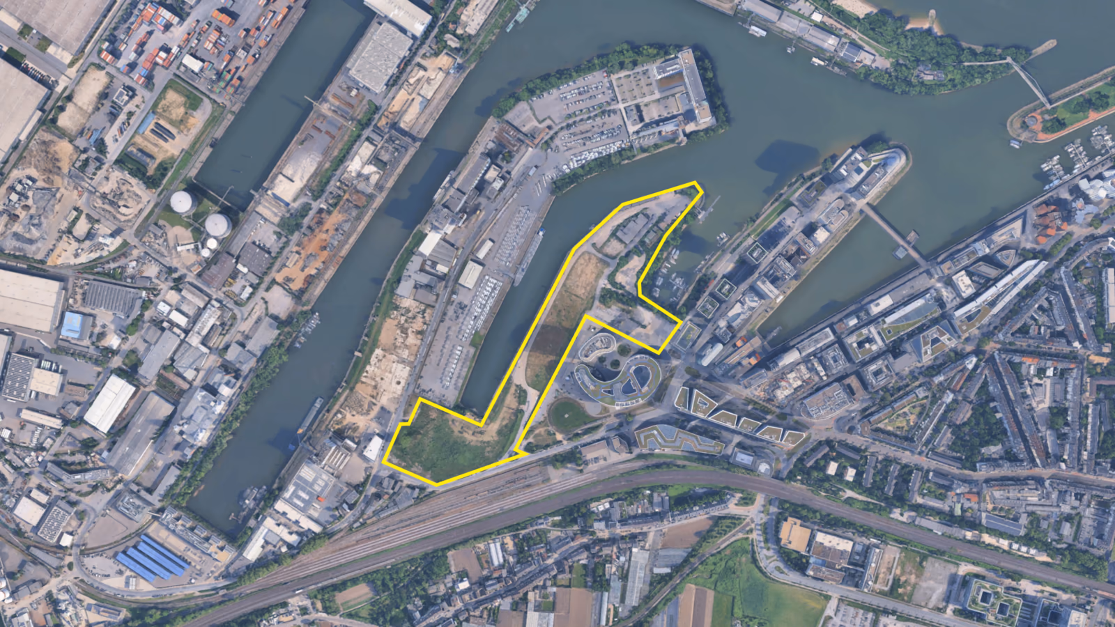 Aerial view of Düsseldorf’s Medienhafen, with the site of the future campus outlined in yellow between the harbor basins.